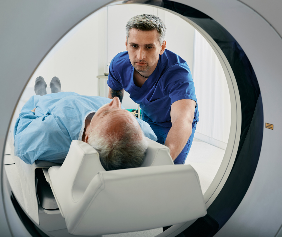 Older man entering CT scan machine with male attendant watching over him