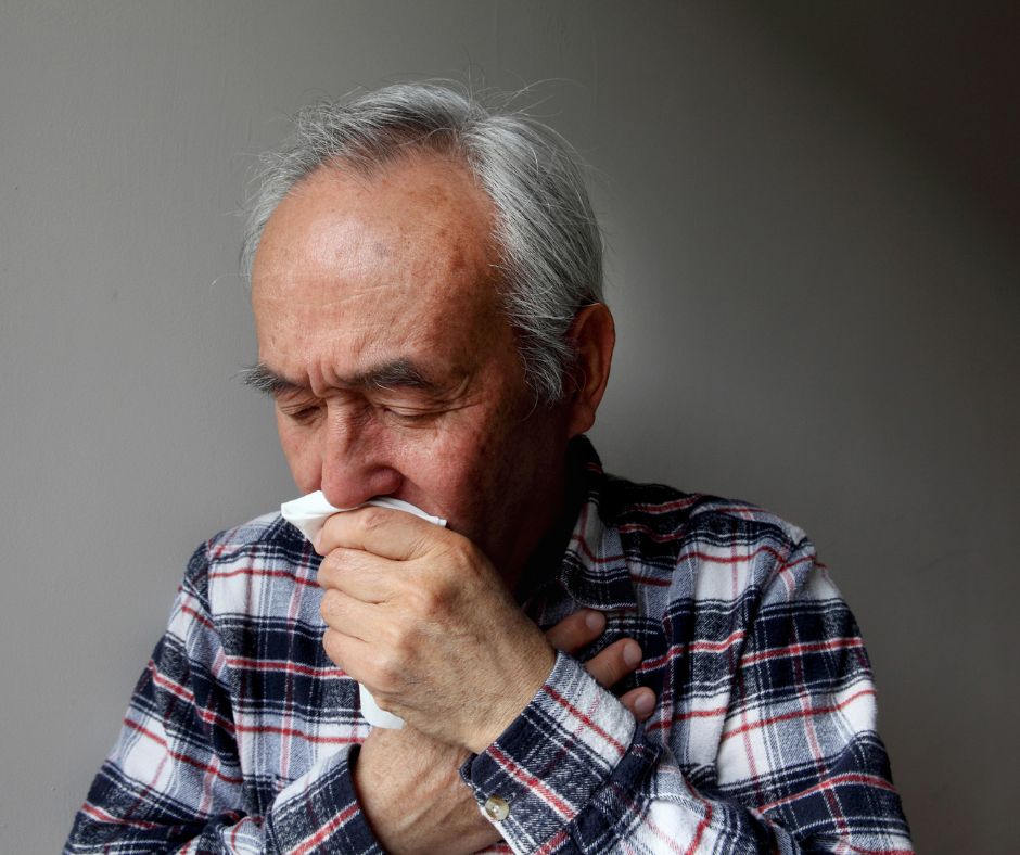Older man coughing into a tissue