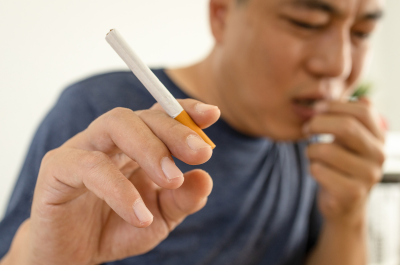 Closeup of man coughing while holding a cigarette