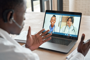 Doctor on computer meeting with two doctors on screen